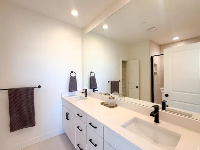 Light, bright, and designed for gathering, this spacious kitchen features crisp white cabinetry, abundant storage, a large center island with seating, modern pendant lighting, and a gas range. Expansive windows bring in natural light and showcase the surr