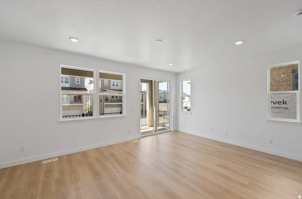 Spacious room featuring light wood-finish flooring, recessed lighting, and multiple windows