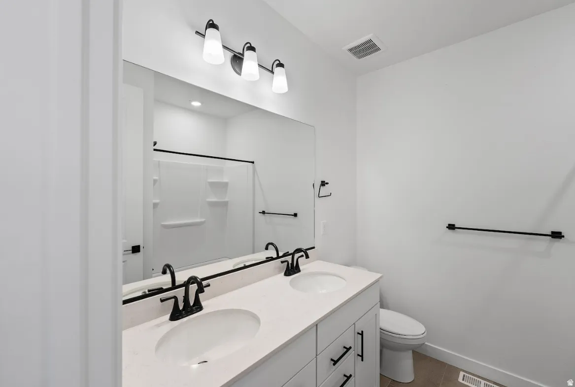 Dual vanity with white cabinetry, light-toned countertop, and matte black fixtures