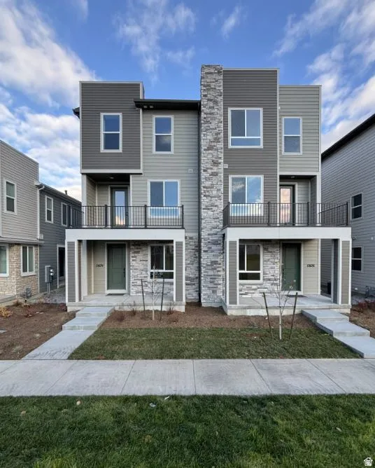Modern townhome exterior featuring multi-toned siding, stone veneer accents, and contemporary black-framed windows