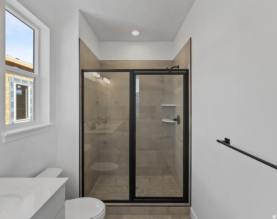 Frameless glass shower enclosure with matte black hardware, tiled shower walls, and a tiled shower pan