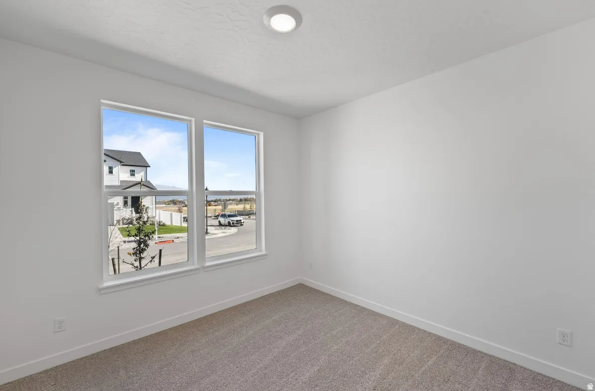 Room featuring two large windows, neutral-toned carpeting, white walls, and a recessed ceiling light