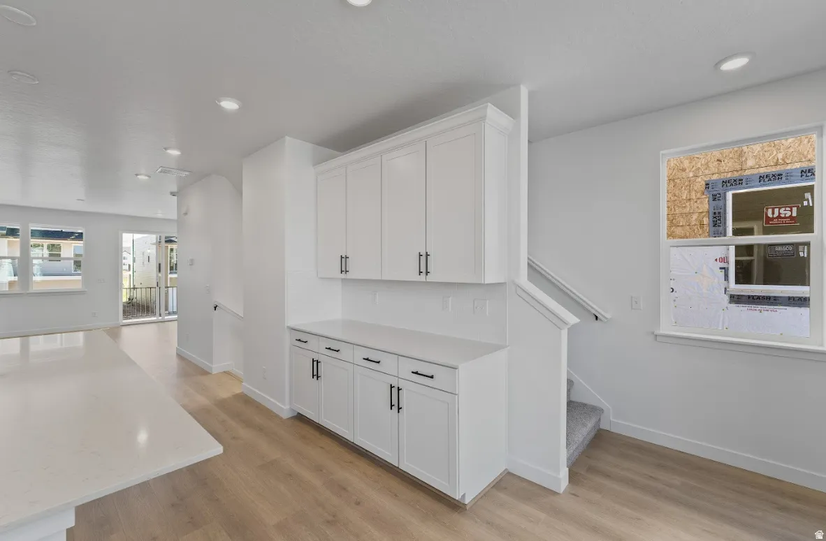 Built-in white cabinetry with matte black hardware, quartz-finish countertop, and recessed lighting
