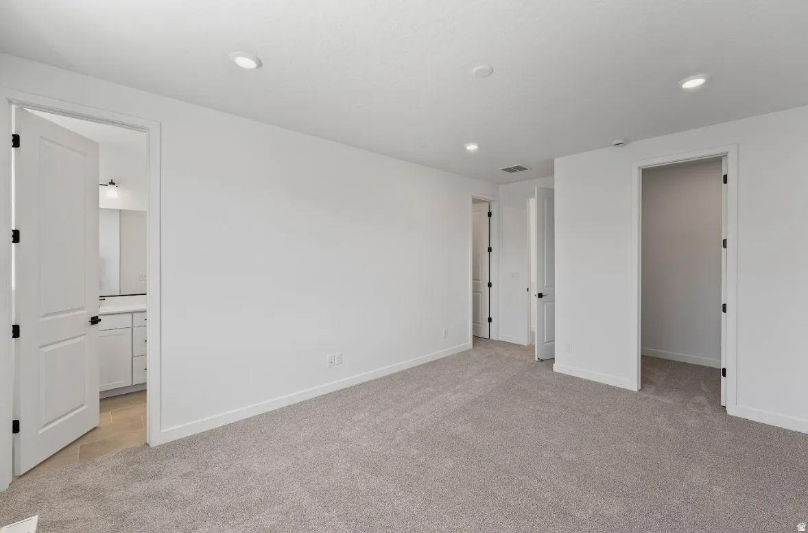 Spacious room featuring gray carpet flooring, recessed lighting, and white walls