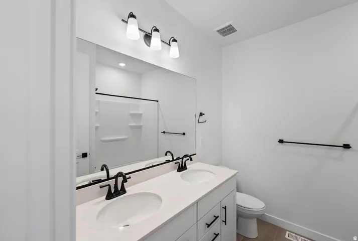 Dual vanity with white cabinetry, light-toned countertop, and matte black fixtures