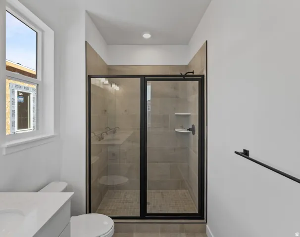 Frameless glass shower enclosure with matte black hardware, tiled shower walls, and a tiled shower pan