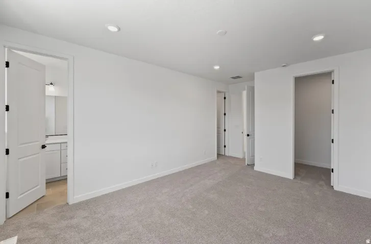 Spacious room featuring gray carpet flooring, recessed lighting, and white walls