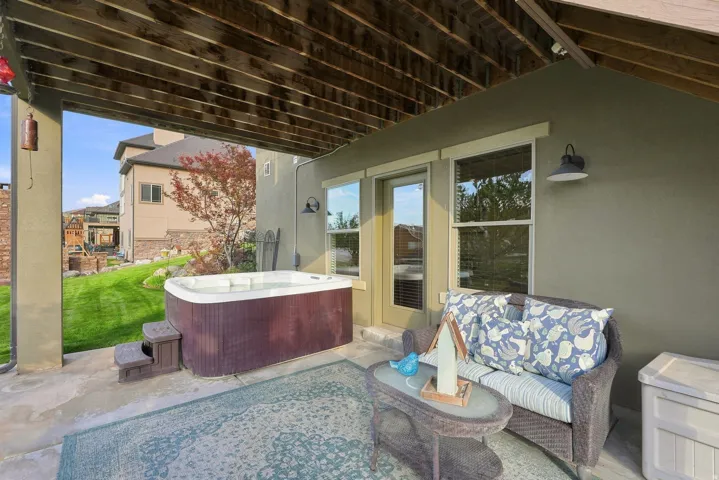 Covered patio featuring a built-in hot tub, concrete flooring, exterior wall sconce, and a wood-slat ceiling