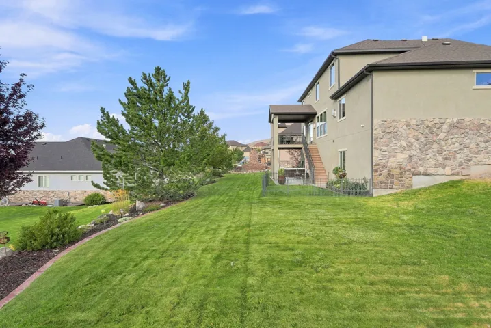 Expansive sloped lawn with mature trees and shrubbery