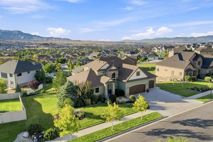 Expansive property featuring a paved driveway, attached garage, manicured lawn, and mature landscaping