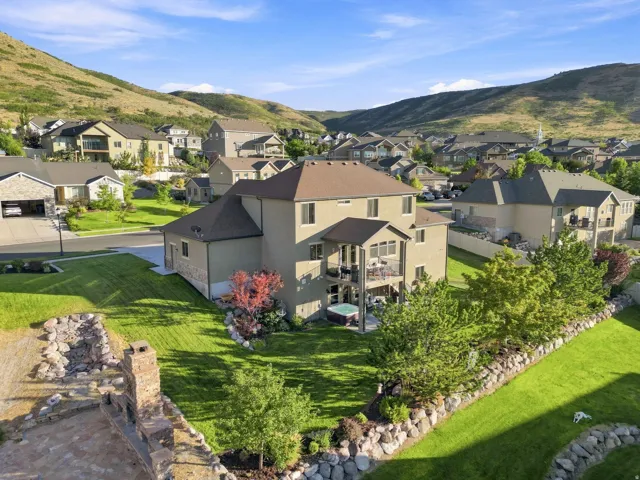 Expansive backyard featuring a stone retaining wall, mature trees, and a built-in outdoor fireplace