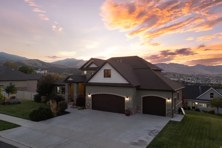 Contemporary architectural style featuring a multi-gabled roofline, stone and siding exterior, an attached two-car garage, and a concrete driveway