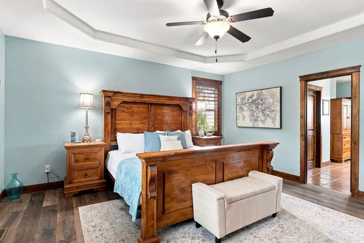 Wood-finish flooring throughout, tray ceiling with a ceiling fan, and a wood-trimmed doorway
