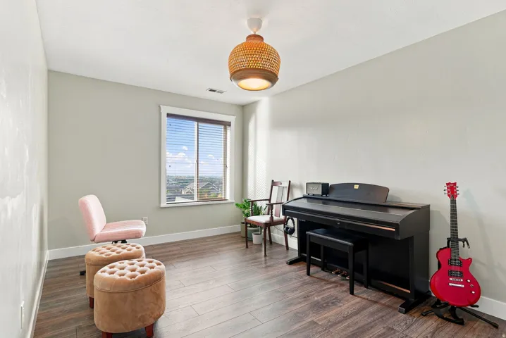 Upstairs bedroom #3. Wood-finish flooring, single window with blinds, ceiling-mounted light fixture, light-toned walls