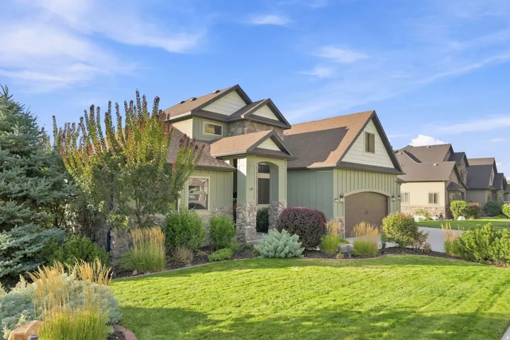 Gable rooflines, stone and siding exterior, arched entry, mature landscaping, and an attached garage