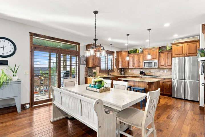 Hardwood-style flooring throughout, kitchen with wood-finish cabinetry, stainless steel appliances, and a tiled backsplash