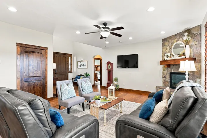 Living area featuring wood-finish flooring, a stone-clad fireplace with a wood mantle, and recessed lighting