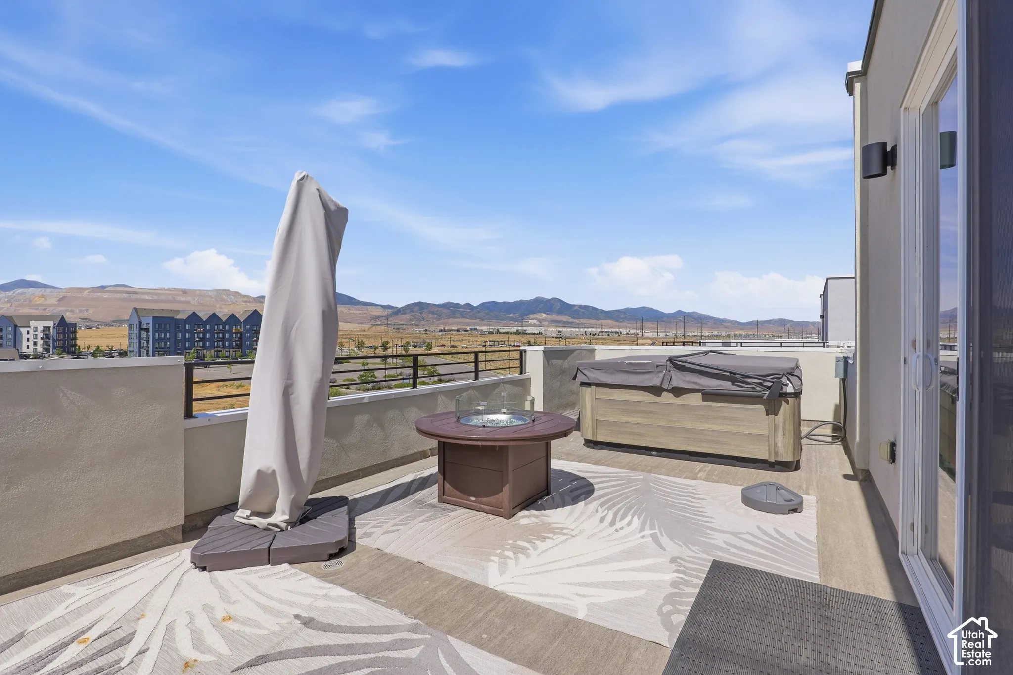Rooftop patio featuring expansive hardscaping, a built-in fire pit, and a hot tub