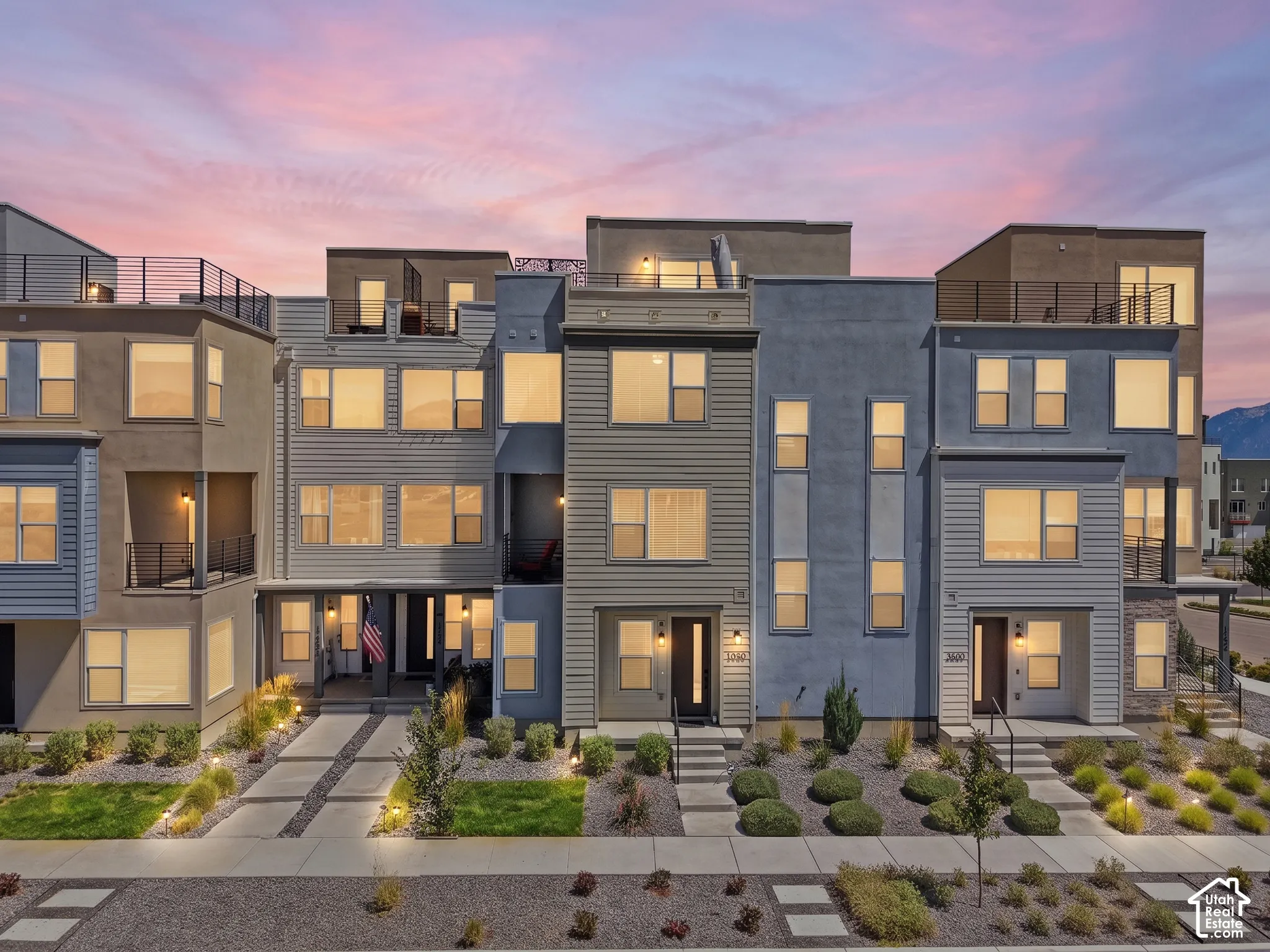 Contemporary multi-story facades with varied siding, rooftop patios with metal railings, and integrated exterior lighting