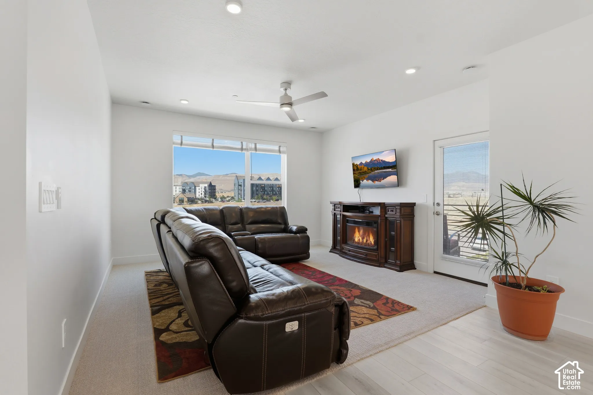 Spacious living area featuring large windows, a built-in electric fireplace, recessed lighting, and a ceiling fan