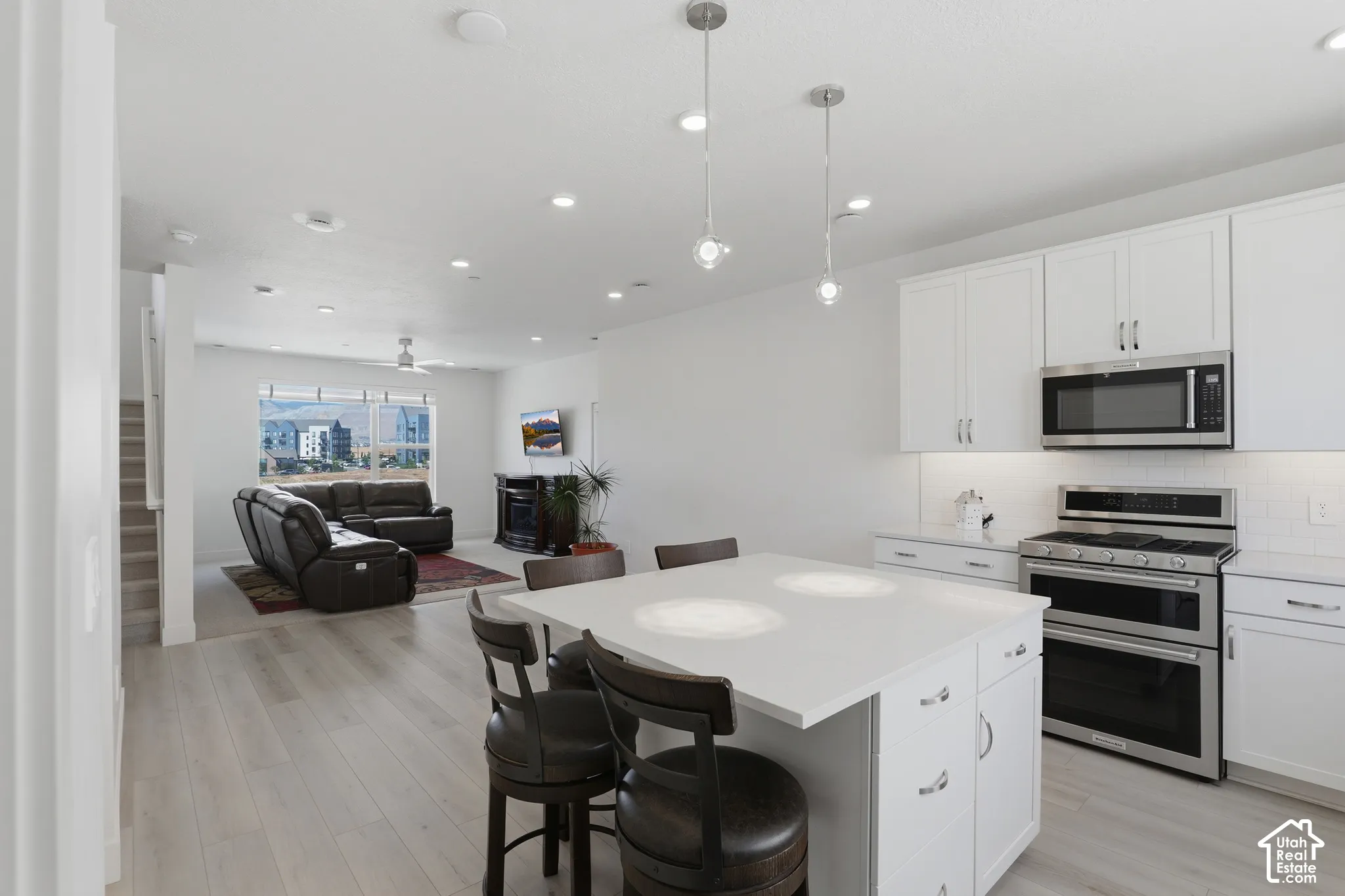 Open-concept design featuring a modern kitchen island with seating, stainless steel appliances, white cabinetry, and recessed lighting