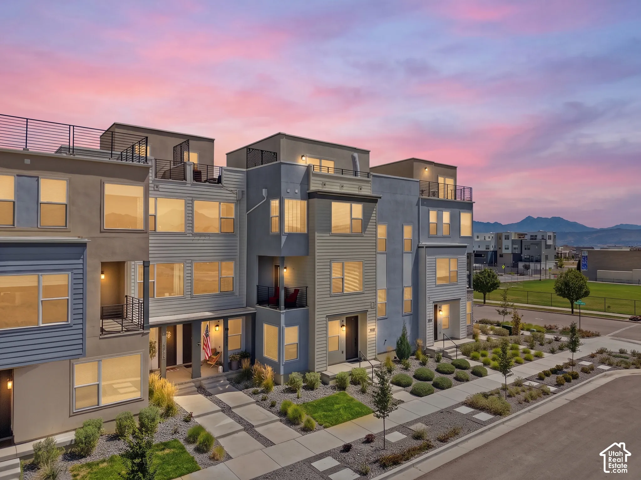 Contemporary multi-level townhome featuring a rooftop deck with metal railings and an exterior of mixed siding and stucco