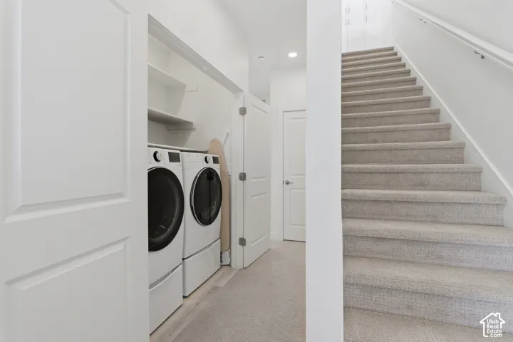 Full-size laundry appliances with built-in shelving, complemented by a carpeted staircase with a white handrail