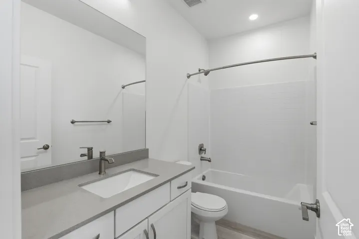 Modern bathroom featuring a single vanity with a gray countertop, an integrated rectangular sink, a brushed nickel faucet, and a white bathtub with a subway tile surround