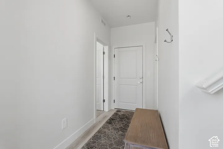 White interior doors, light wood-finish flooring, and white walls