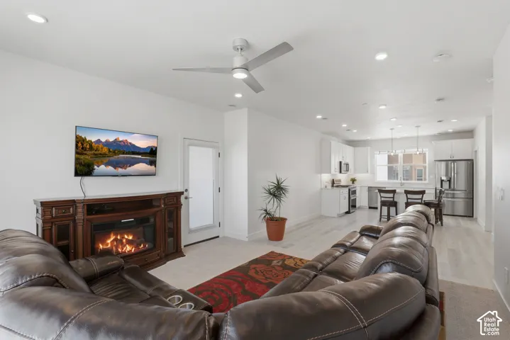 Open-concept living space featuring a fireplace, wood-finish flooring, recessed lighting, and a ceiling fan