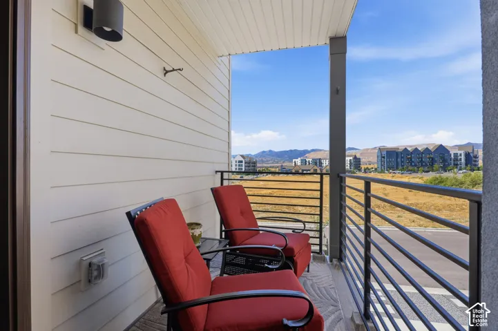 Outdoor balcony featuring a metal railing, durable siding, and an attached outdoor light fixture