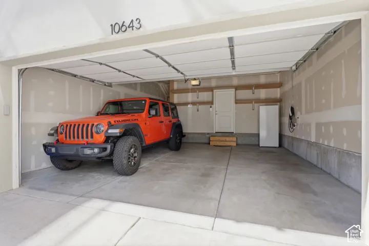 Expansive garage with a concrete floor, built-in shelving, a side access door, and an electric vehicle charging station