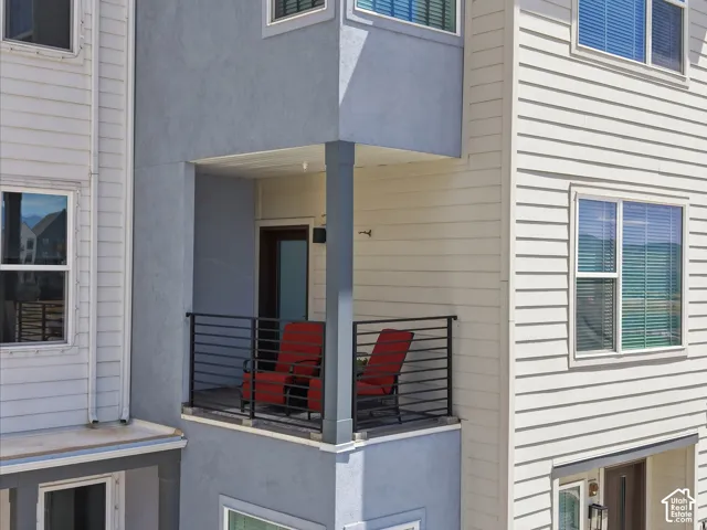 Balcony featuring a dark metal railing, exterior lighting, and a glass-paneled door