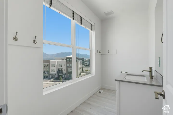 Floor-to-ceiling window, modern vanity with an integrated sink, brushed nickel faucet, and wood-finish flooring