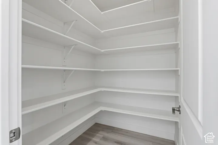 Wraparound shelving with multiple levels, wood-finish flooring, and white painted walls