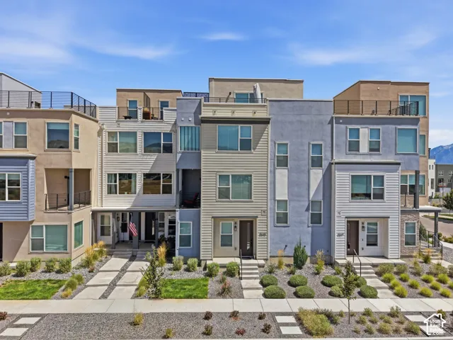 Multi-level townhome featuring a flat roofline, integrated balconies, and a modern facade with varied siding materials