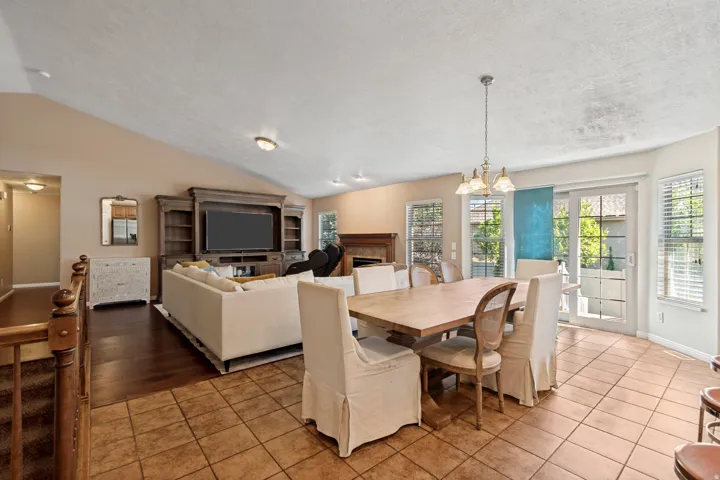 Vaulted ceiling, wood-finish flooring, fireplace, sliding glass door, and tile flooring
