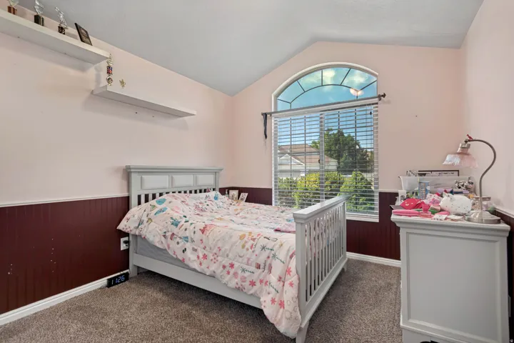 Arch-top window with blinds, vaulted ceiling, and carpeted flooring