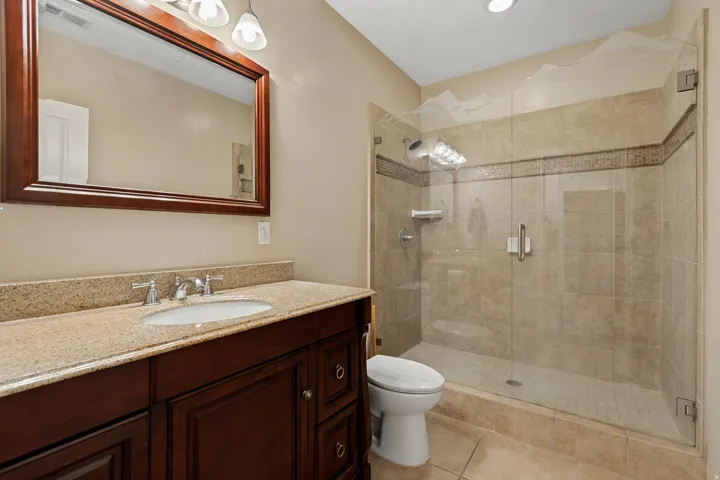 Dark wood-finish vanity with an undermount sink, light-toned stone countertop, and a framed mirror