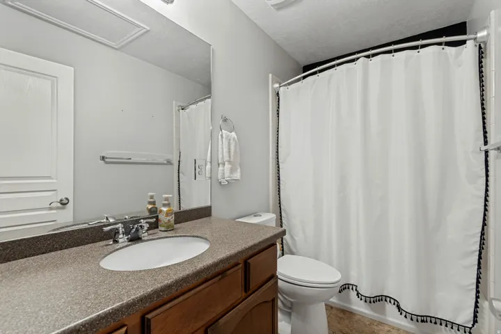 Vanity with a solid surface countertop and undermount sink, wood-finish cabinetry, and a full-width mirror