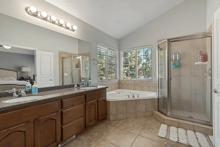 Dual sink vanity with brown cabinetry and a large mirror