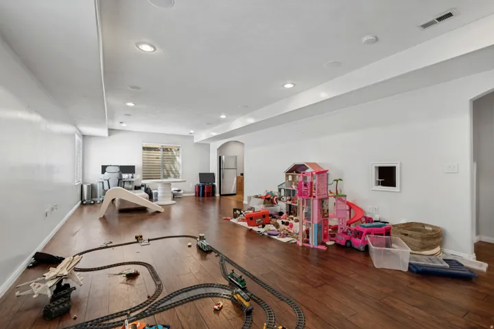 Recessed lighting illuminates the spacious room with wood-finish flooring