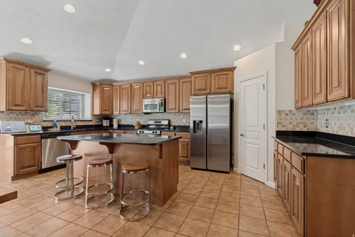 Kitchen featuring wood cabinetry, stainless steel appliances, a center island with countertop seating, and tile flooring
