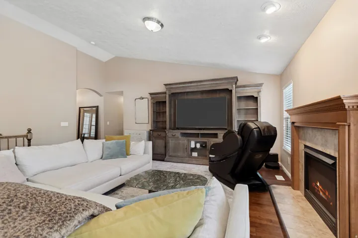 Vaulted ceiling with recessed lighting, built-in entertainment center, and a tiled fireplace with a wood mantel