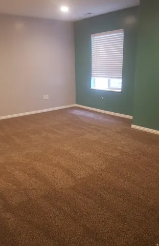 Recessed ceiling lighting, durable carpeting, window with privacy blinds, and neutral wall tones