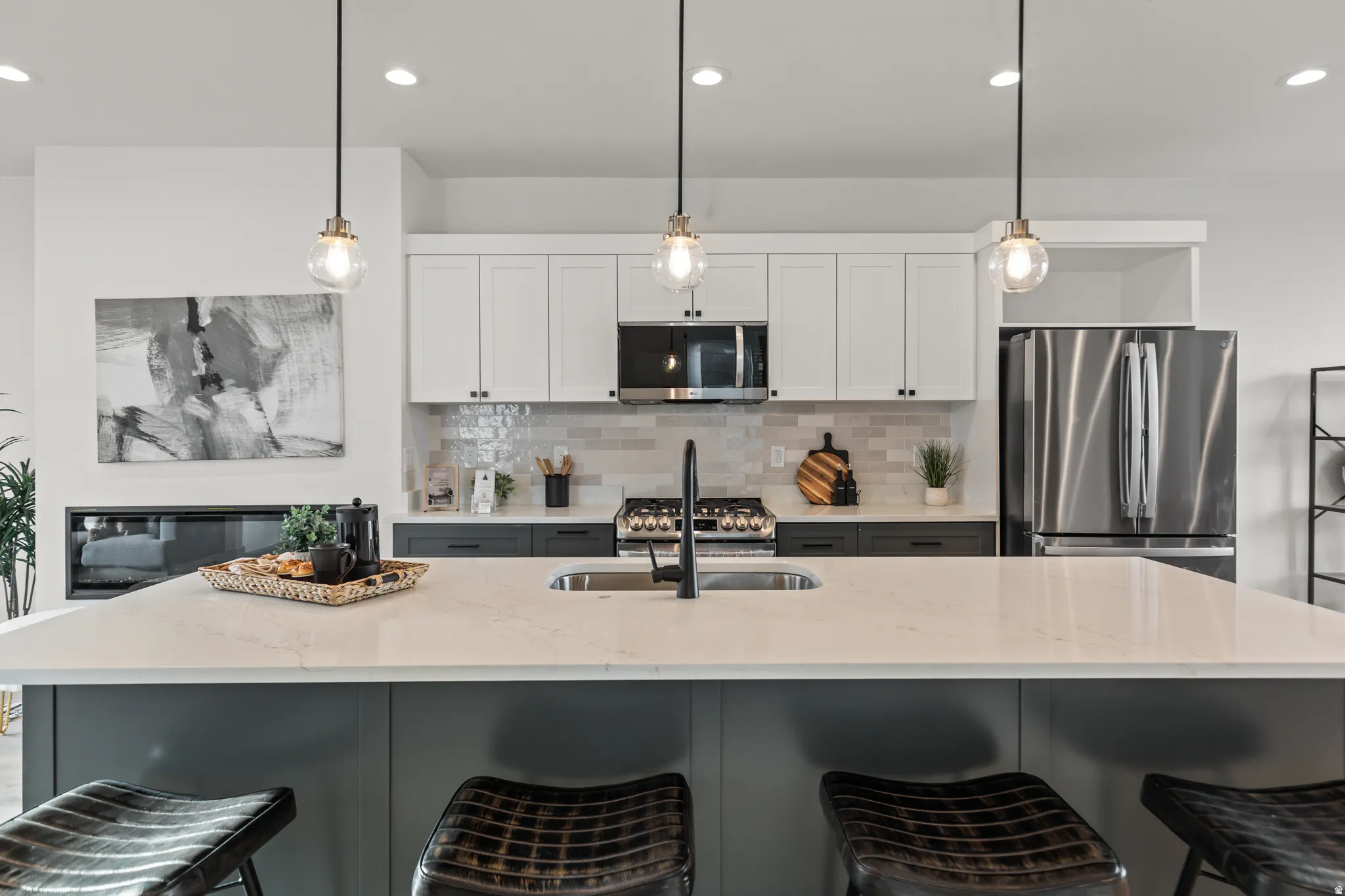 Kitchen featuring an expansive island with a built-in sink, pendant lighting, stainless steel appliances, and two-tone cabinetry