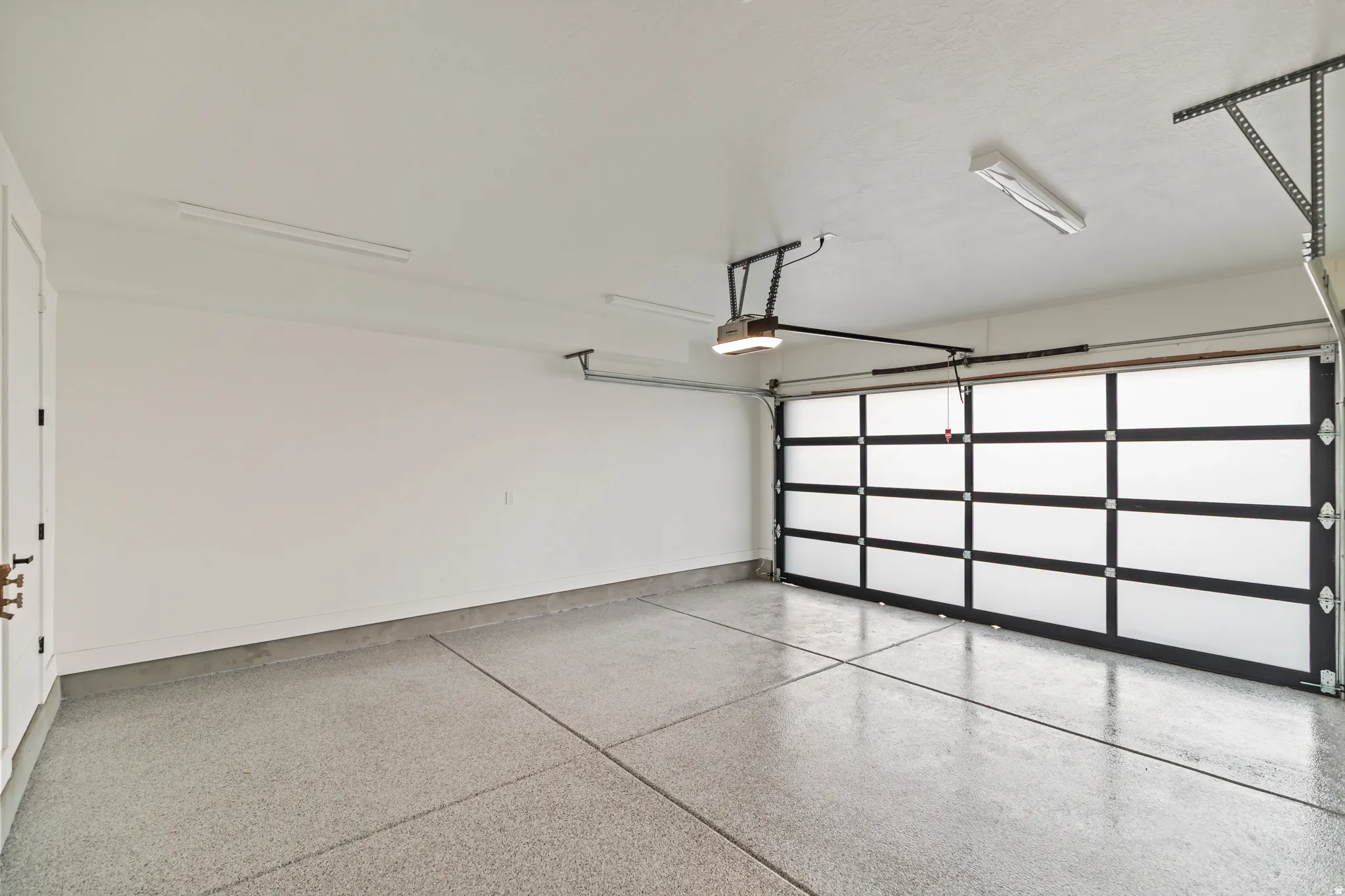 Modern garage door with frosted panels, automatic opener, and epoxy flooring