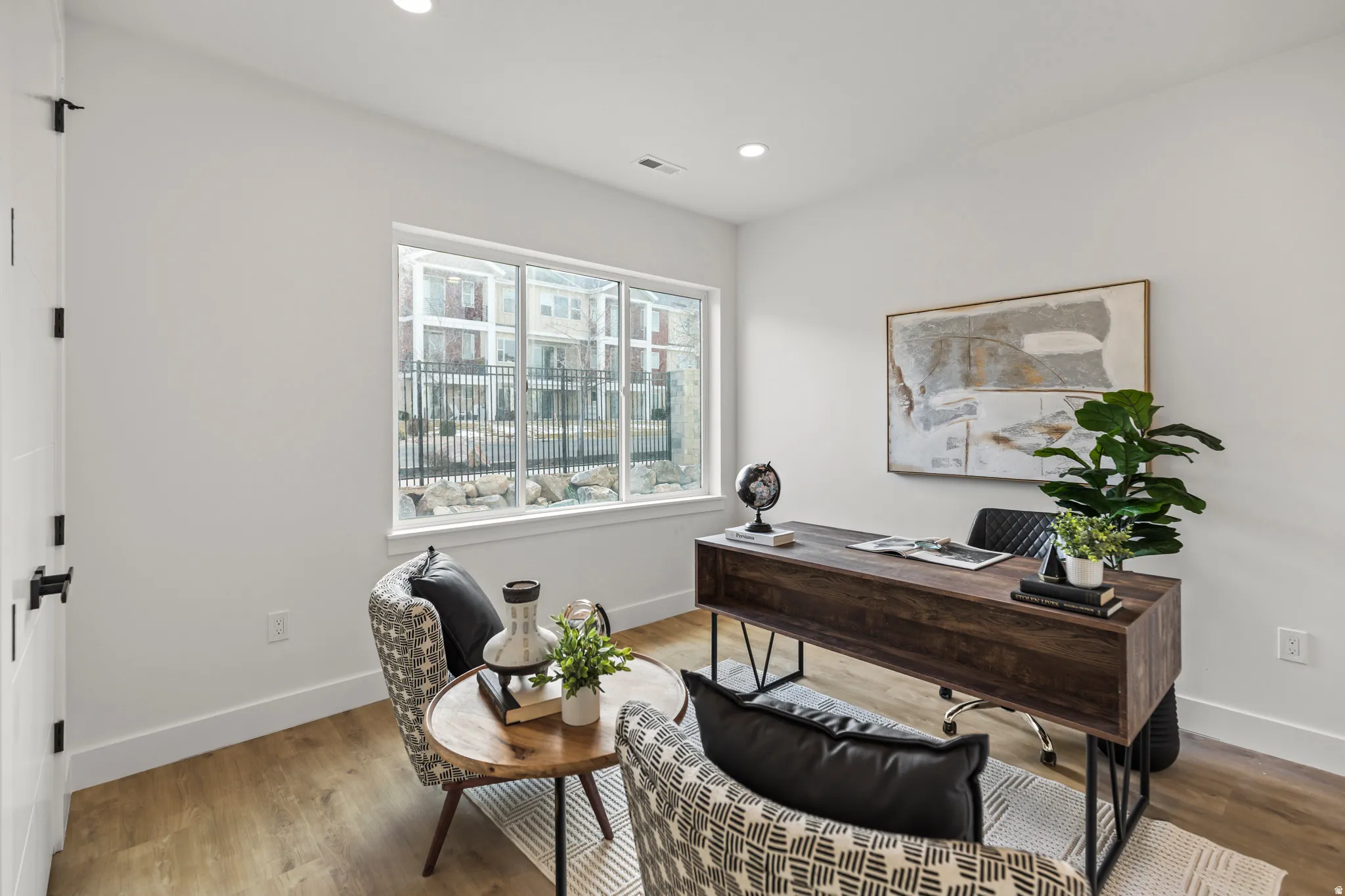 Recessed lighting, wood-finish flooring, white walls, and a large window with white trim
