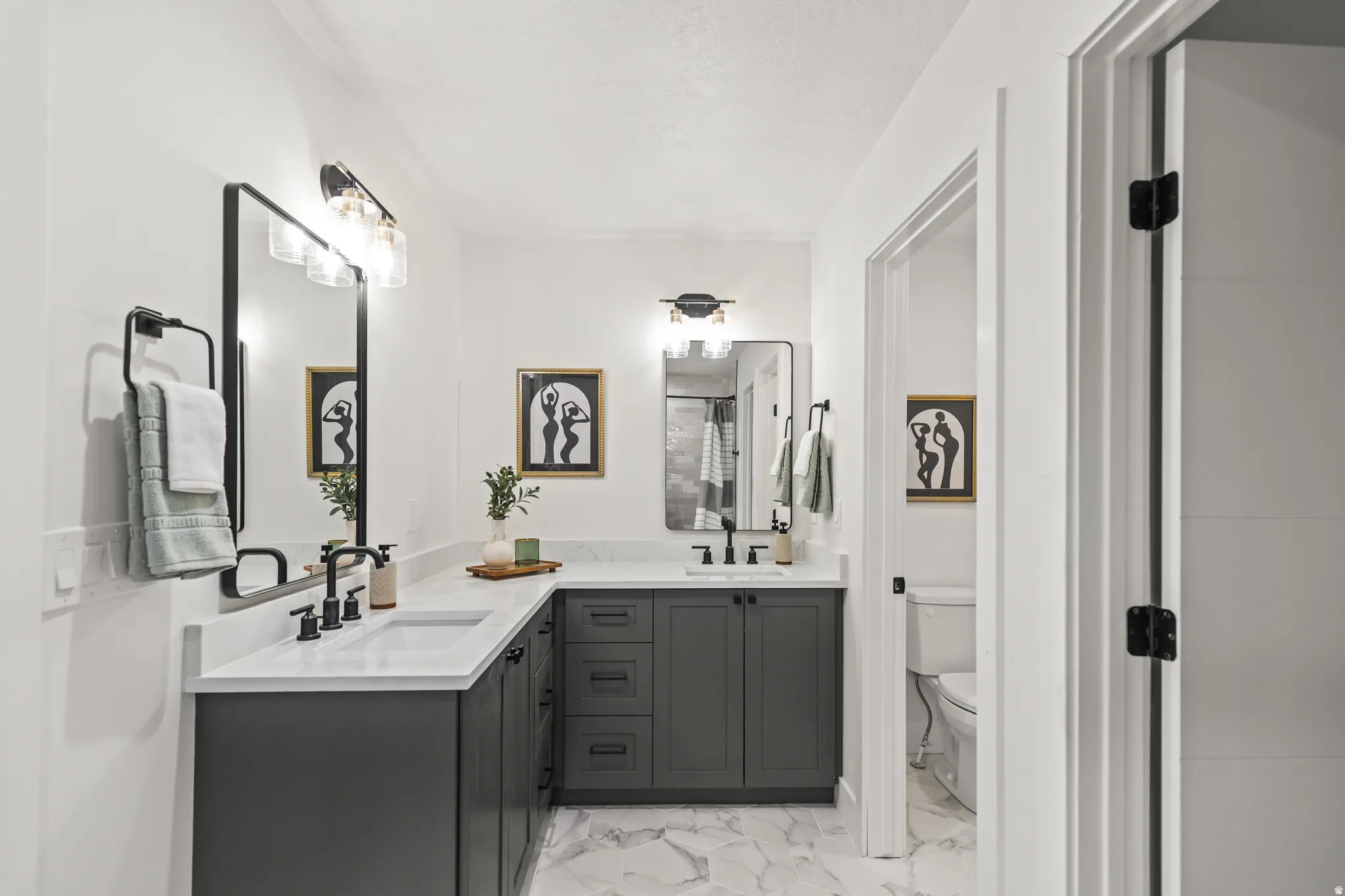 Double vanity with white countertops and undermount sinks, black framed mirrors, and black hardware