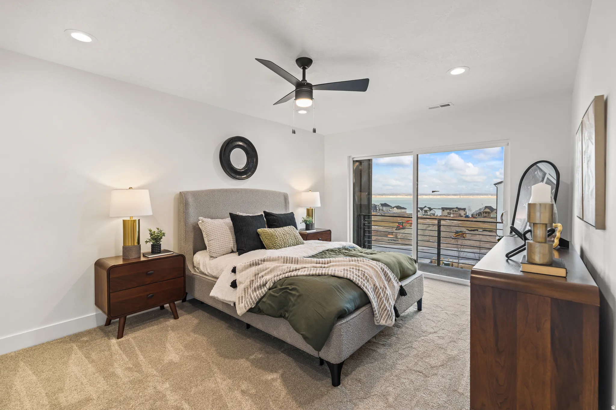 Sliding glass door, private balcony with metal railing, recessed lighting, ceiling fan, and light-colored carpet